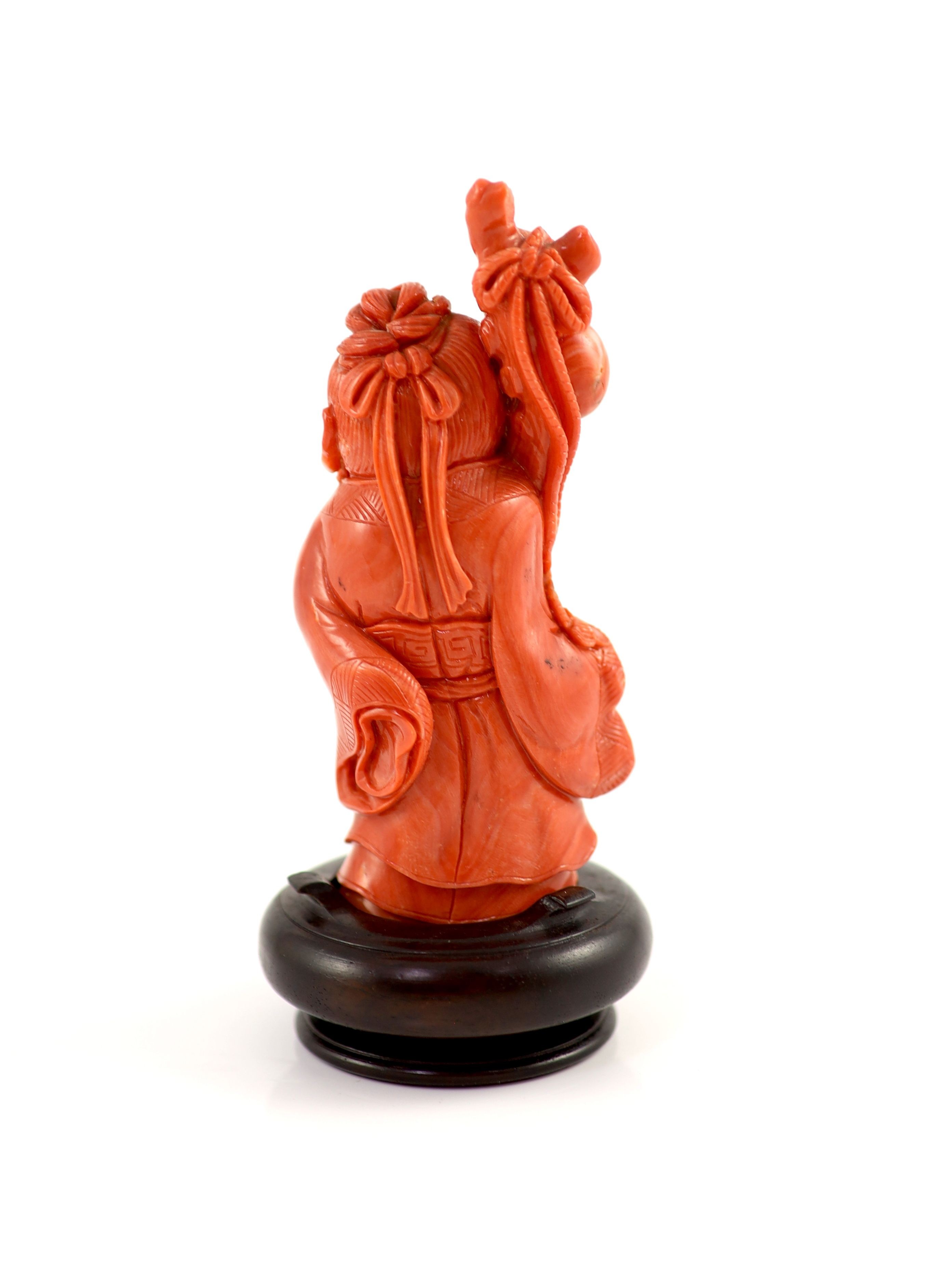 A Chinese coral standing figure of Shou Lao, mid 20th century, 11 cm high, 187g, wood stand